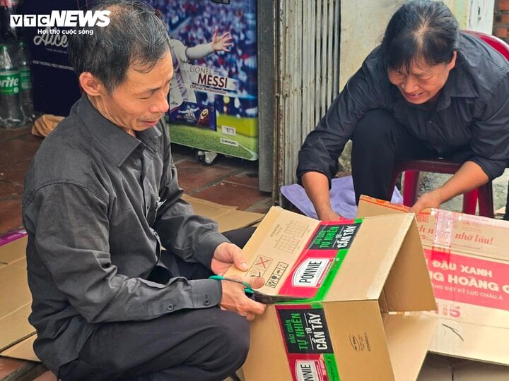 Hai vợ chồng ở làng Lại Đà cùng cắt những miếng bìa để du khách làm quạt.