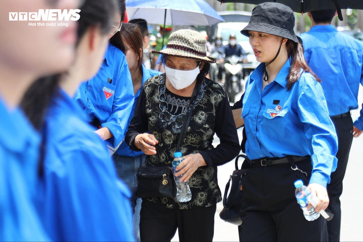 12h30, tại tuyến đường Lê Đức Thọ, thanh niên tình nguyện đưa người già, trẻ nhỏ qua đường, sắp xếp cho họ chỗ đứng để chờ đoàn xe chở di hài Tổng Bí thư đi qua.