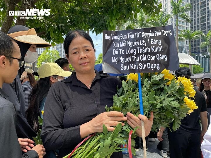 Để tỏ lòng thành kính đến Tổng Bí thư Nguyễn Phú Trọng, một người dân của làng Phú Mỹ thức dậy từ 4h sáng đến chợ hoa Tây Tựu mua 1.100 bông hoa cúc vàng đem đến phát cho người dân đứng hai bên đường tiễn biệt Tổng Bí thư lần cuối.