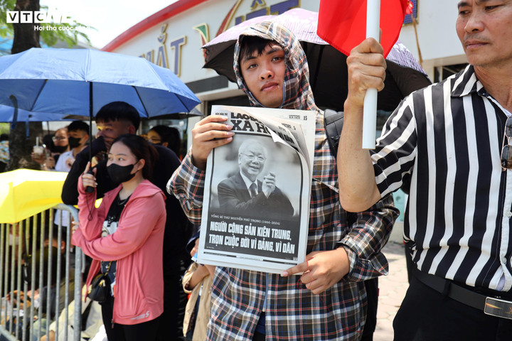 Rất nhiều bạn trẻ mang theo ảnh của Tổng Bí thư Nguyễn Phú Trọng đứng trước khu vực nghĩa trang Mai Dịch chờ đoàn xe đi qua.