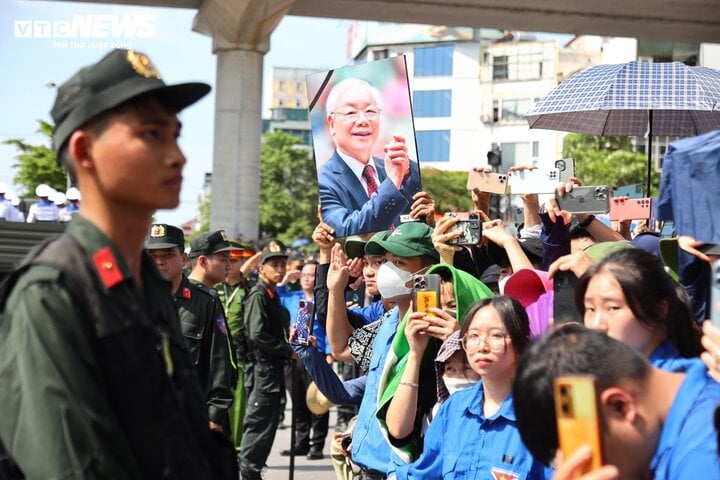 Nhiều người trân trọng giương cao di ảnh của Tổng Bí thư Nguyễn Phú Trọng để tiễn biệt ông.