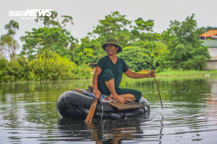 Bác Lý Thị Hồng chèo chiếc "thuyền" bằng lốp ô tô đi tìm đàn vịt. (Ảnh: Đức Anh)