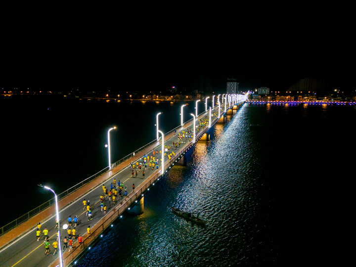 Các vận động viên chạy qua cầu Nhật Lệ dưới ánh đèn lung linh chiếu sáng.