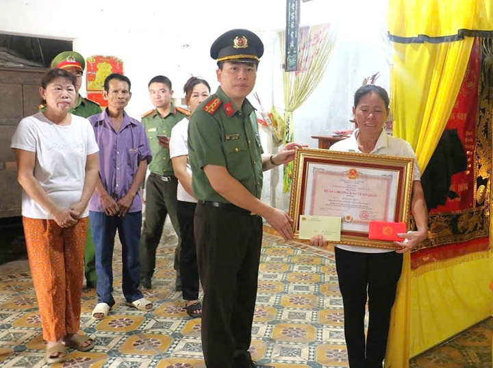 Phó Giám đốc Công an tỉnh trao Huân chương Bảo vệ Tổ quốc hạng Ba đến thân nhân ông Hoàng Thế Thắng. (Ảnh: CANA)