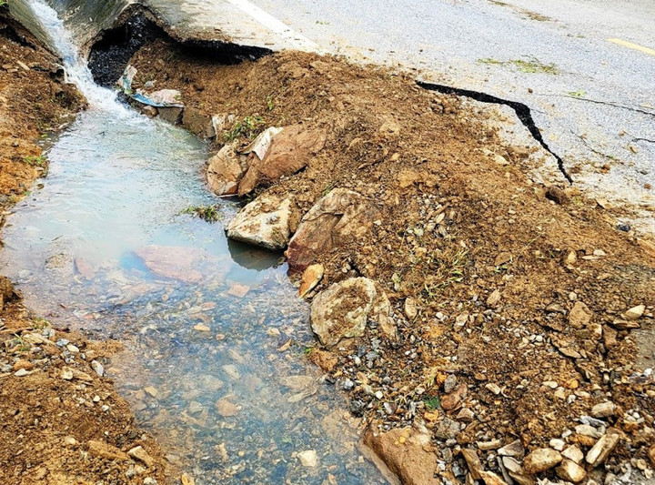 Do mưa lớn, lượng nước nhiều khiến rãnh thoát không kịp, tràn lên làm hư hỏng mặt đường. (Ảnh: CTV)