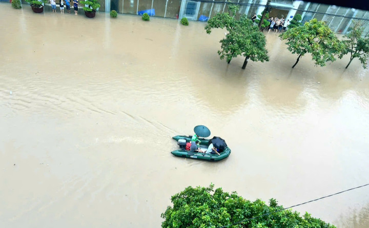 Người dân dùng thuyền hơi di chuyển qua những điểm ngập nước.