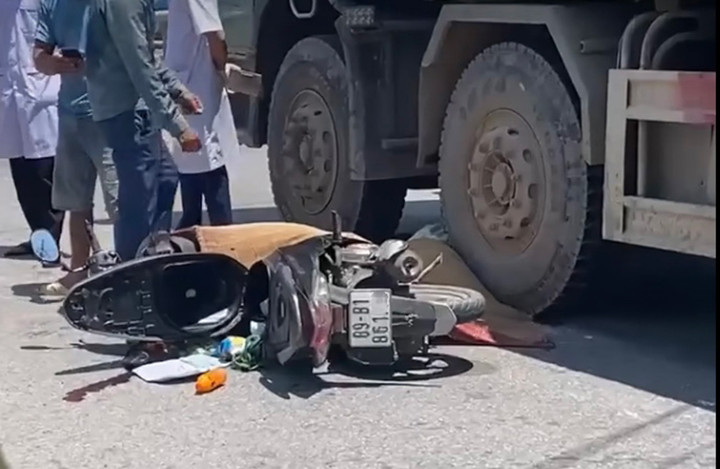 Chiếc xe máy nằm dưới gầm xe tải sau vụ va chạm.