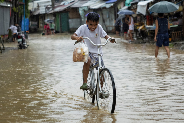 Một cậu bé đạp xe trong mưa lũ do bão Yagi gây ra ở Baras, tỉnh Rizal, Philippines, hôm 2/9. (Ảnh: Reuters)