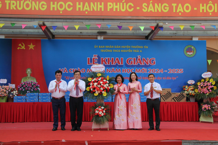 Ông Nguyễn Tiến Minh, Bí thư huyện ủy Thường Tín ( thứ 2 từ trái sang) và ông Nguyễn Như Ý, Trưởng phòng GD&ĐT huyện, tặng hoa chúc mừng nhà trường.