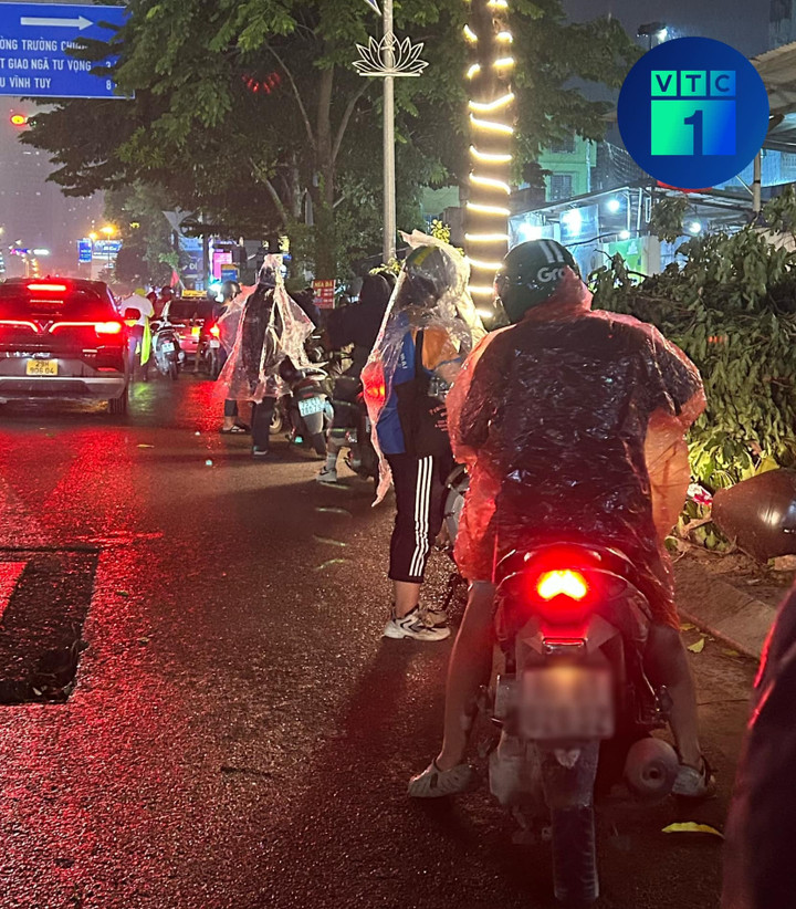 Người dân dừng xe mặc áo mưa tại khu vực Ngã Tư Sở (quận Thanh Xuân).