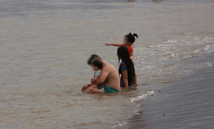 Một gia đình vô tư tắm biển, trong đó có cả con nhỏ.