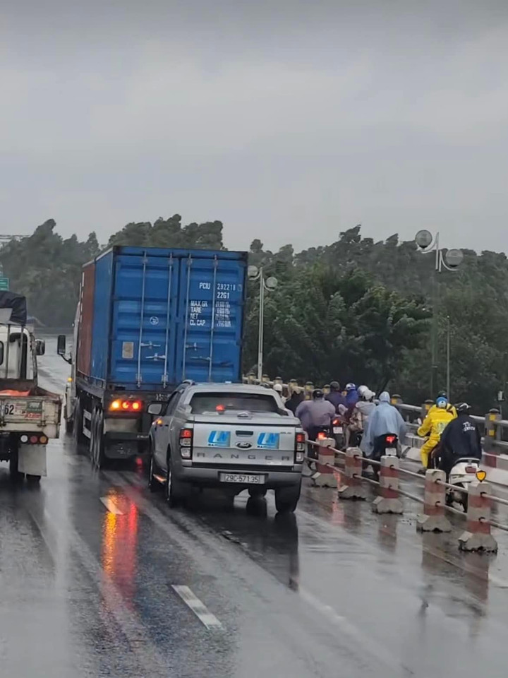 Xe bán tải nối đuôi xe tải để che chắn cho người đi xe máy trên cầu. (Ảnh: Minh Hy)