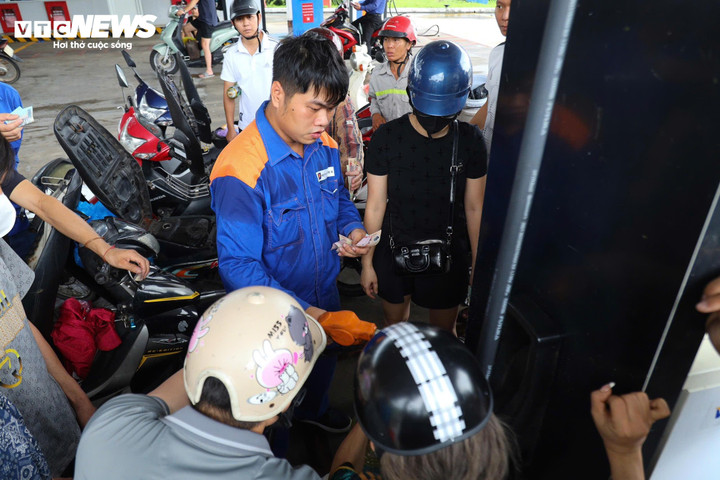 Vây quanh nhân viên bơm xăng là hàng loạt xe máy, bình, can "khát" xăng.