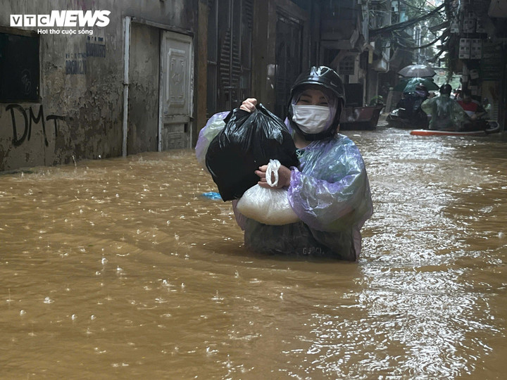 Chị Đông ở phố Hồng Hà phải lội nước ra ngoài mua thức ăn. Chị kể, chiều qua còn chưa có nước, tới sáng nay, nước đã ngập ngang người.