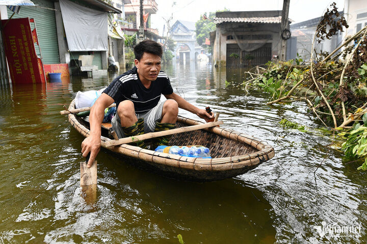 Một người đàn ông vừa được phát nước uống, anh đưa hàng lên thuyền rồi tự chèo về nhà.