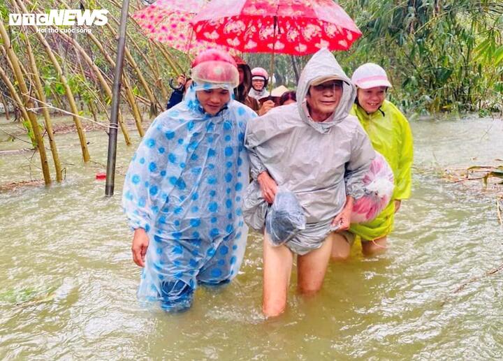 Người dân thôn Thủy Cam (xã Lộc Thuỷ, huyện Phú Lộc) đội mưa, lội nước đi tránh lũ.