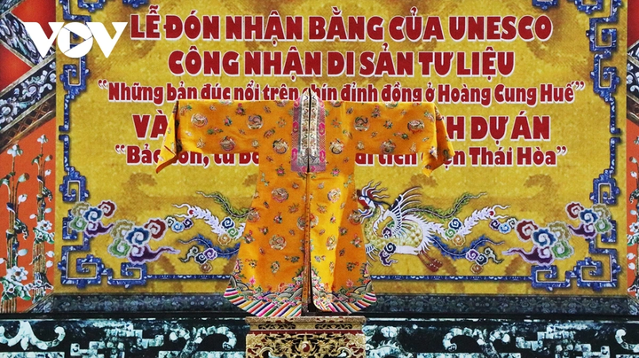 Áo Nhật Bình được thiết kế tinh xảo từ vải sa nam màu vàng đậm.