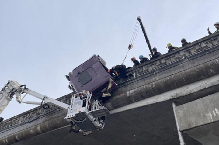 Tài xế mắc kẹt trong đầu xe kéo treo lơ lửng trên thành cầu.