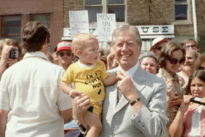 Ông Jimmy Carter chụp ảnh cùng một em bé trong kỳ nghỉ hè năm 1979. Chiếc áo phông của em bé có dòng chữ "I'm a Carter Nut" phía trên hình đậu phộng.