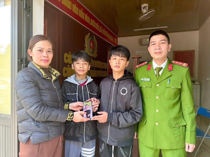 Công an thị trấn Phổ Châu trao trả chiếc điện thoại do hai em Khải và Quân nhặt được cho chị Hòa. (Ảnh: CA Hà Tĩnh)
