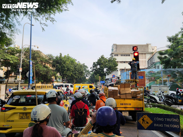 Nhân viên sửa chữa tín hiệu giao thông đang lắp đặt dèn tín hiếu mũi tên xanh cho phép xe máy được rẽ phải khi đèn đỏ.