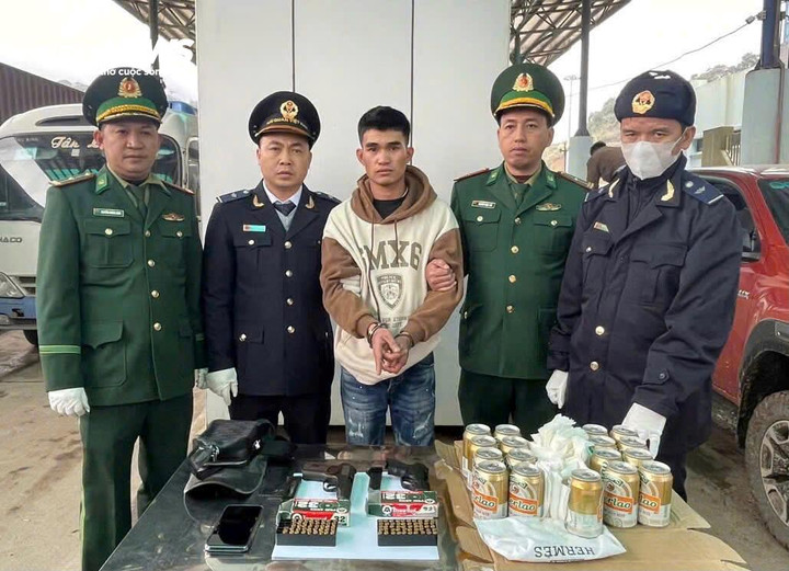 Cao Bá Huy cùng số tang vật là hai khẩu súng ngắn và 92 viên đạn được nguỵ trang kỹ trong thùng bia. (Ảnh: BPCC)