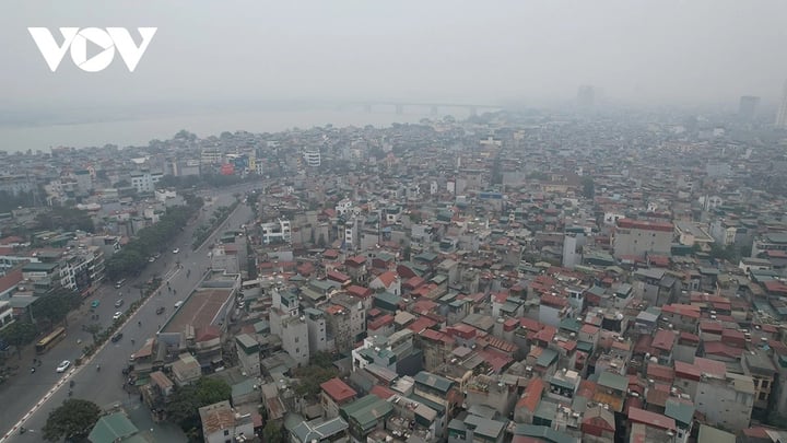 Phía xa cầu Vĩnh Tuy bắc qua sông Hồng nối quận Long Biên với quận Hai Bà Trưng mờ mờ sau làn sương bụi.