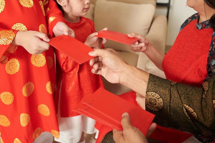 Phụ huynh nên đưa con cầm tiền lì xì từ sớm để học cách quản lý tài chính. (Ảnh: Shutterstock)