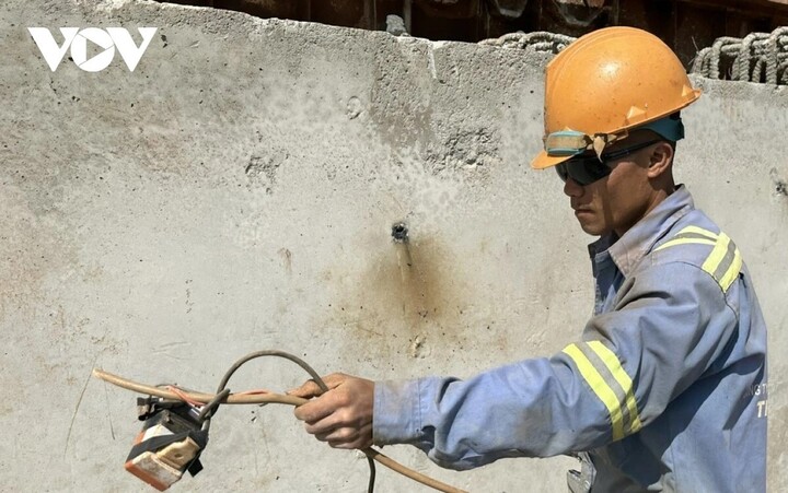 Một công nhân thuộc Công ty cổ phần xây dựng và lắp máy Trung Nam thực hiện việc hàn gia cố trụ móng đường. Những công nhân ra quân từ Mồng 2 Tết, được thanh toán chế độ tăng ca theo quy định. Bên cạnh đó là tiền lì xì từ công ty, với mức 500 nghìn đồng/người.