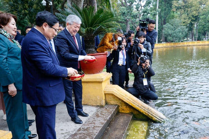 Hai Thủ tướng thăm ao cá Bác Hồ nằm ngay trước khuôn viên nhà sàn và cho cá ăn. (Ảnh: VGP/Nhật Bắc)