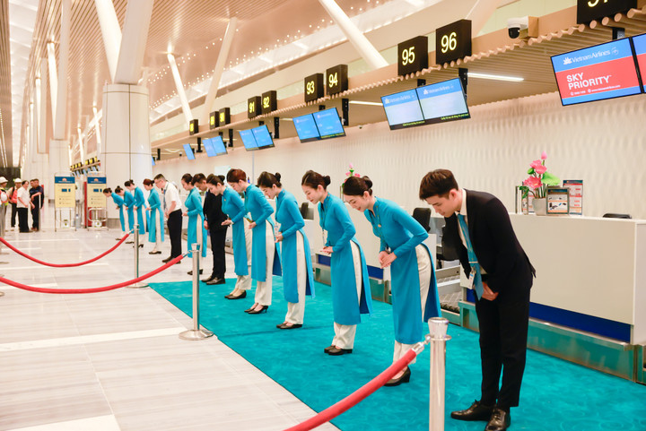 Nhân viên Vietnam Airlines cúi chào đầu ca trực, sẵn sàng phục vụ những hành khách đầu tiên của nhà ga T3 Tân Sơn Nhất.