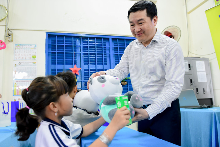Các em học sinh đón nhận sữa, gấu bông và các món quà khác từ Vinamilk.