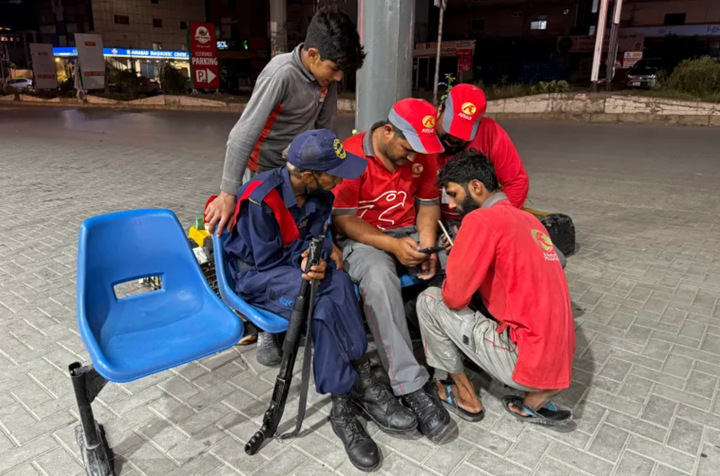 Nhân viên theo dõi tin tức trên điện thoại di động tại một trạm xăng ở Islamabad vào ngày 7/5/2025 (Ảnh: Al Jazeera)
