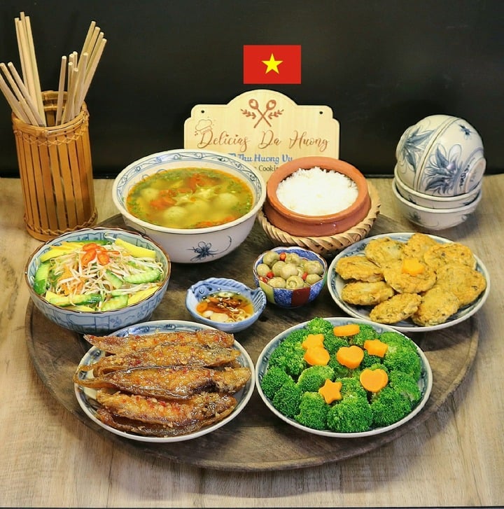 Mâm cơm có các món cá bơn chiên mắm tỏi, hoa lơ luộc, chả cá thác lác, canh chua cá thác lác, nộm dưa giá.