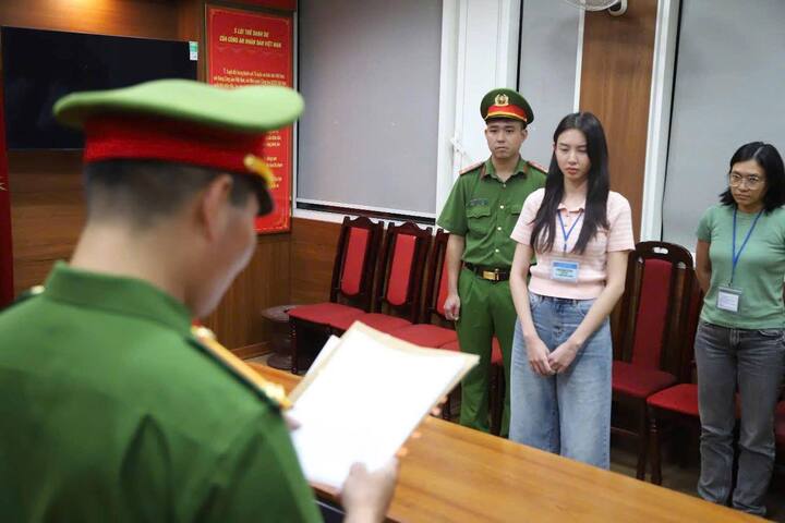 Hoa hậu Thùy Tiên (phải) nghe cảnh sát đọc lệnh khởi tố, bắt tạm giam. (Ảnh: Bộ Công an)