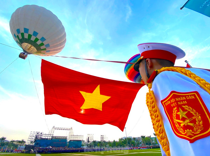 Lá đại kỳ Tổ quốc rộng 2.025m2 từ từ được kéo lên cao giữa nền trời xanh biếc trong tiếng nhạc, tung bay mạnh mẽ trong gió. Hình ảnh ấy khiến cả quảng trường như lặng đi trong niềm xúc động.