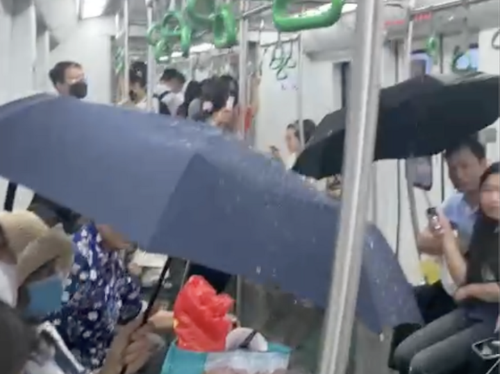 Người dân phải lấy ô che trên chuyến tàu metro Cát Linh- Hà Đông vào chiều 19/5.