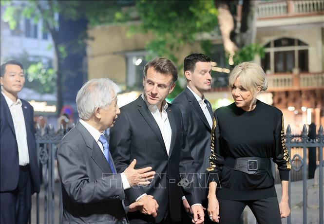 Tổng thống Pháp Emmanuel Macron và Phu nhân nghe giới thiệu về nét văn hóa phố cổ Hà Nội. (Ảnh: TTXVN)