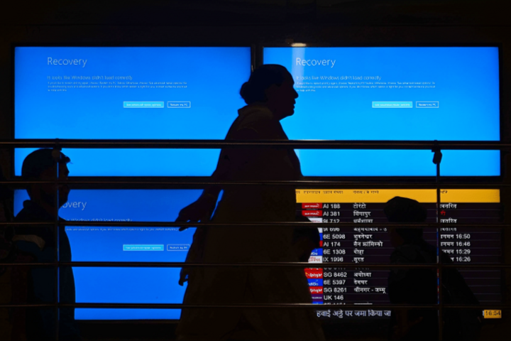 Du khách đi ngang qua màn hình sau khi sự cố gián đoạn lớn trong dịch vụ đám mây của Microsoft gây ra tình trạng hủy chuyến bay và chậm chuyến. (Nguồn: nbcnews.com)