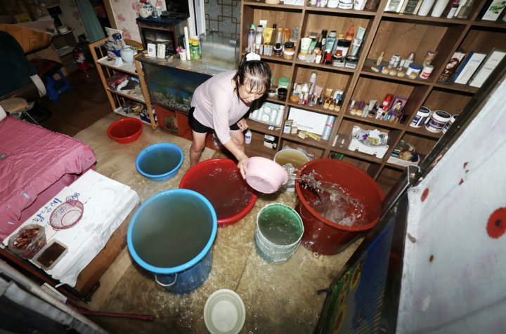 Người dân đang sử dụng xô, chậu trong nhà để dọn dẹp sàn tiệm làm tóc bị ngập do mưa lớn tại Gwangju. Tại nhiều khu dân cư khác như Chaewoon-dong (Dangjin), tầng hầm chung cư cũng bị ngập sâu khiến hàng chục phương tiện hư hỏng.