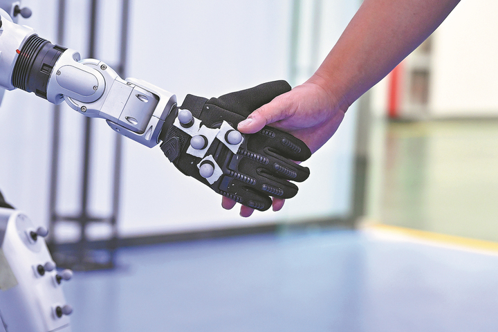 Một robot hình người bắt tay với một nhân viên tại một công ty thiết bị thông minh. (Nguồn: Xinhua)