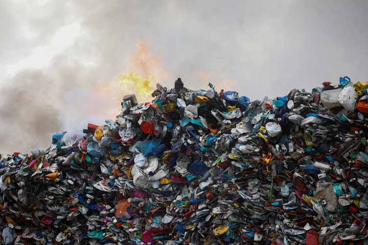 Dưới lớp khói mù mịt là tiếng kêu cứu của Trái Đất — mỗi mảnh nhựa cháy là một vết thương môi trường. (Nguồn: Reuters)
