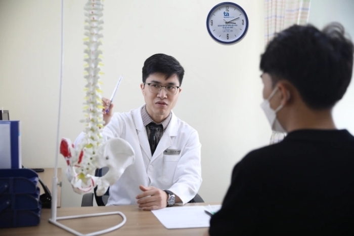 Bác sĩ Thắng khám cho người bệnh trẻ tuổi bị thoái hóa cột sống. (Ảnh minh họa: BVCC)