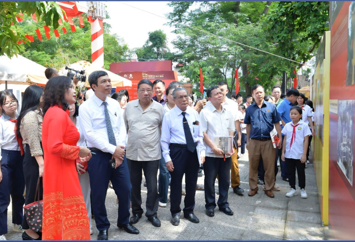 Các đại biểu, nhà khoa học và các em học sinh chăm chú tham quan, tìm hiểu các tư liệu tại khu vực trưng bày.
