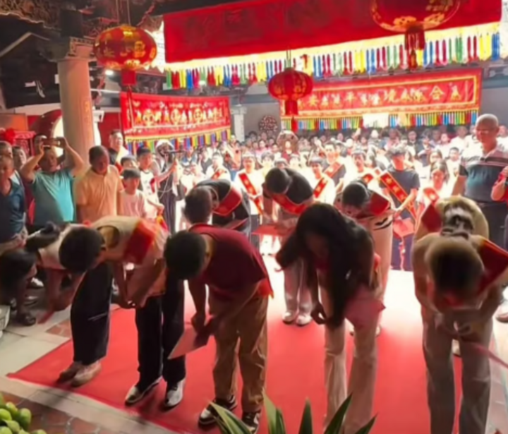 Trong buổi lễ, những tân sinh viên thành đạt khoác dải băng đỏ in dòng chữ “vinh quang của tổ tộc” đã dâng hương và cúi lạy trước bàn thờ tổ tiên. (Ảnh: SCMP/Jimu)