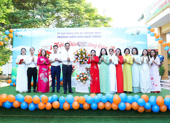 Lãnh đạo xã Thượng Phúc tặng hoa chúc mừng thầy, trò trường Mầm non Quất Động. (Ảnh: Hương Phạm)