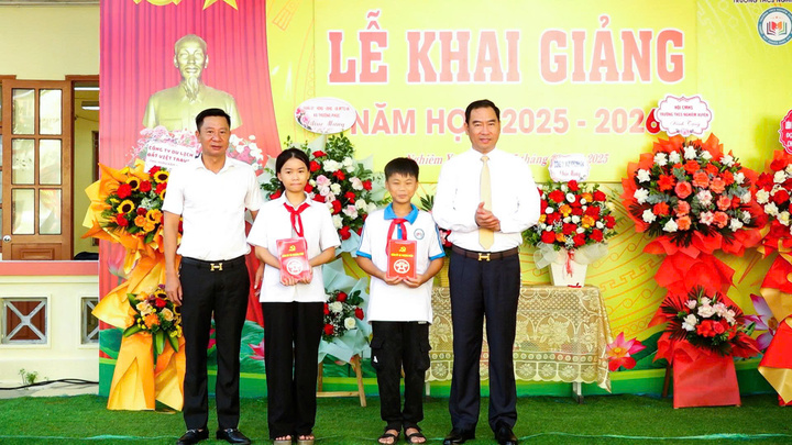 Ông Tạ Hữu Thọ, Bí thư Đảng ủy xã Thượng Phúc (bên phải) tặng quà cho các em có hoàn cảnh khó khăn trường THCS Nghiêm Xuyên nhân dịp khai giảng. (Ảnh: Hương Phạm)