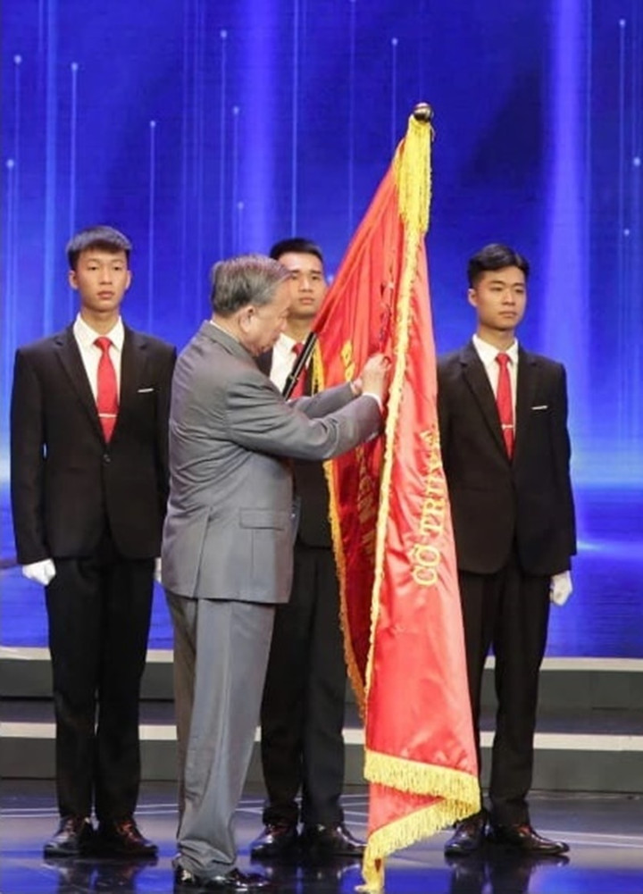 Tổng Bí thư Tô Lâm gắn Huân chương Lao động hạng Nhất lên lá cờ truyền thống của Đài Truyền hình Việt Nam. (Ảnh: VTV)