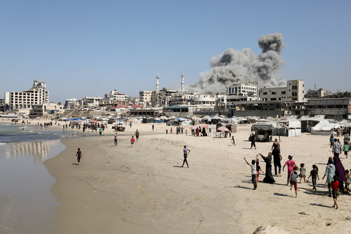 Người dân đi gần tòa tháp Al-Ghefari trúng tên lửa của Israel.