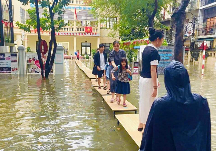 Trường THCS &THPT Nguyễn Tất Thành kê bàn thành lối đi để học sinh không phải lội nước ra về giờ tan trường. (Ảnh: PHCC)